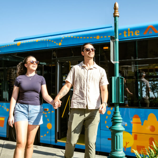 A man and woman exiting a blue ART Bus, while smiling and holding hands.