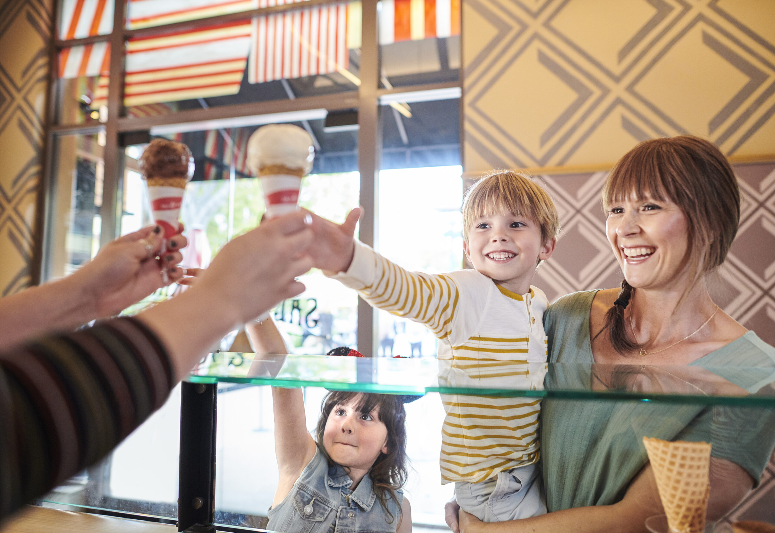 Kids excitingly reach for their freshly scooped ice cream cones